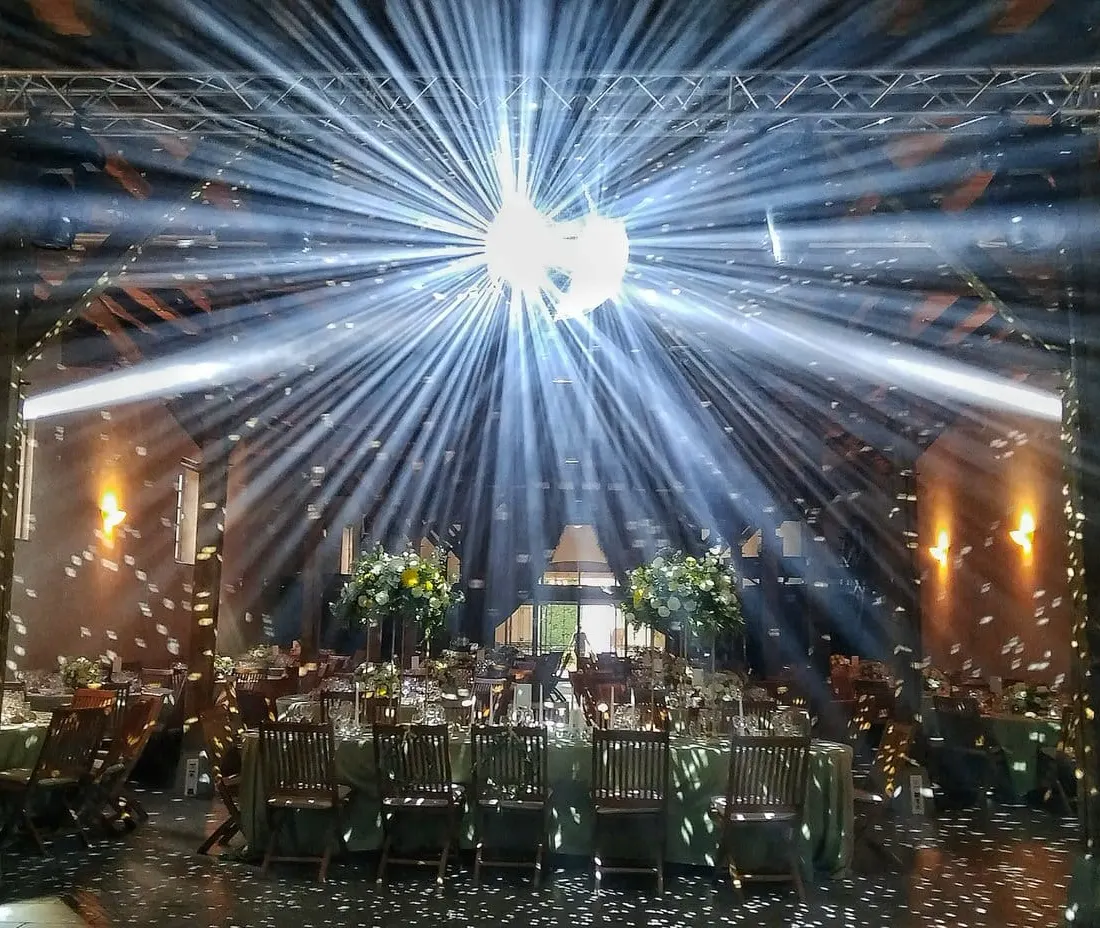 Boule à facettes envoyant des faisceaux blancs au-dessus des tables, dans une grange