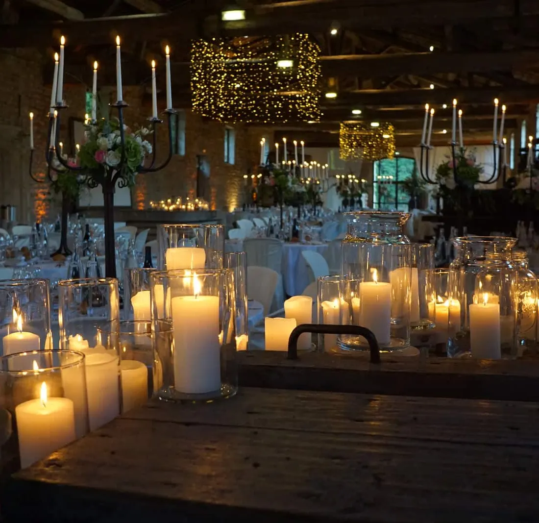Longue table dressée couverte de bougies et de candélabres dans une grange en pierre